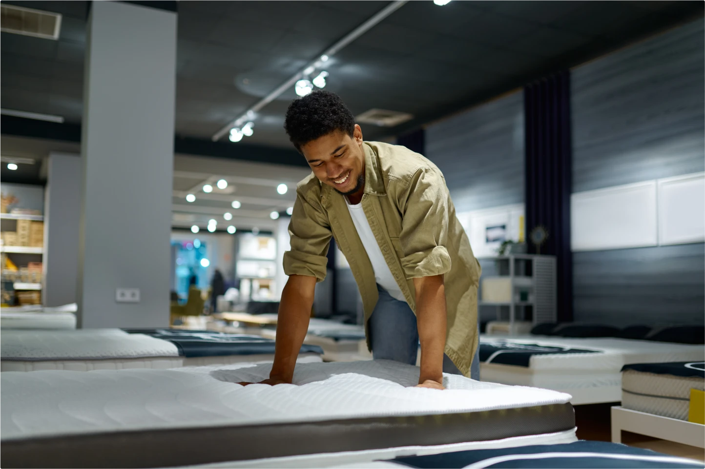 Man smiling and feeling mattress inside a mattress store